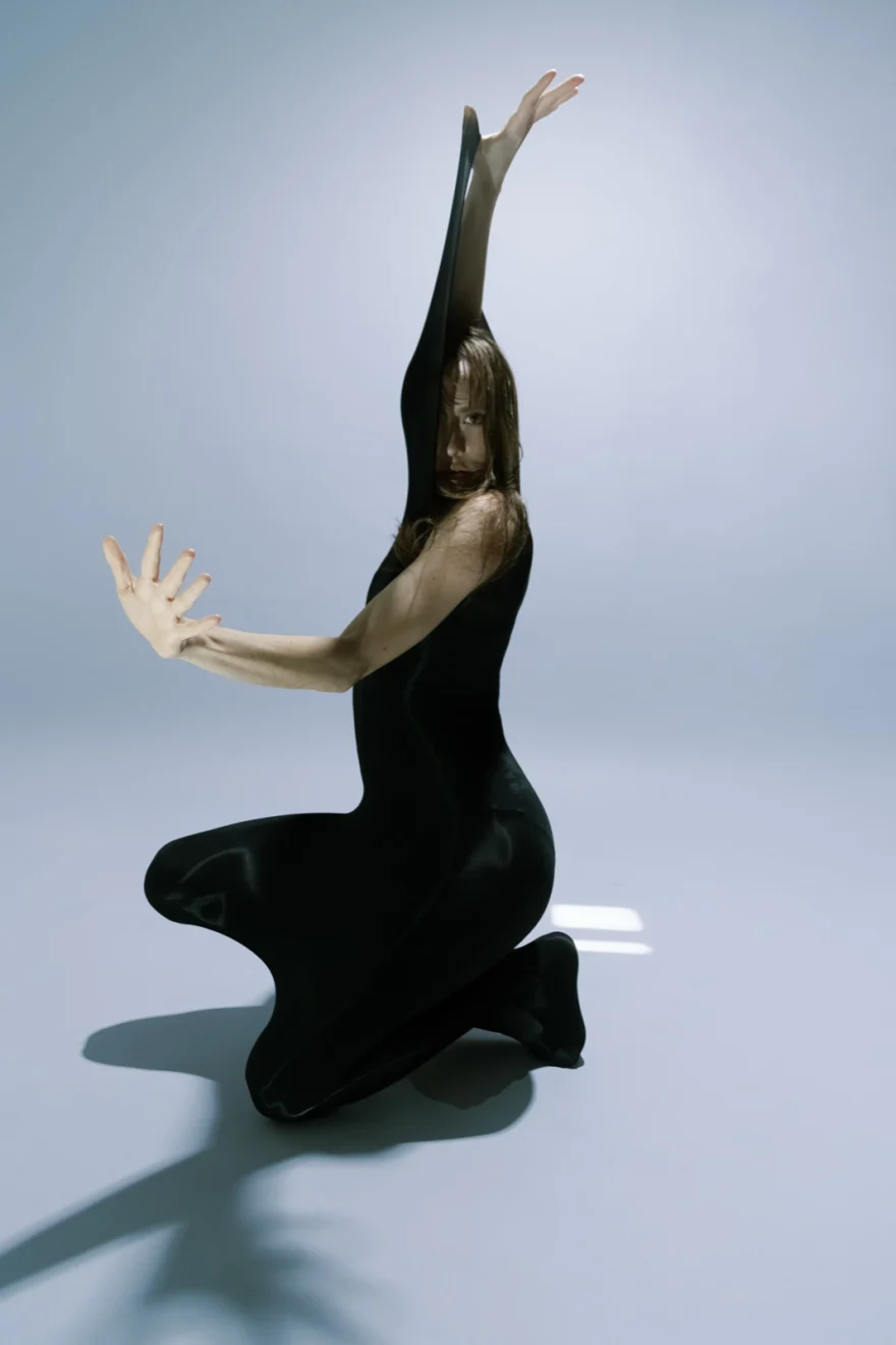 Dancer in a black dress with arms raised in a studio dance pose, SHOT Magazine editorial photographed by Ina Cenusa