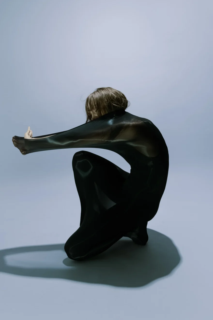 Dancer crouching with one leg extended, black dress on a pale studio floor, SHOT Magazine editorial photographed by Ina Cenusa