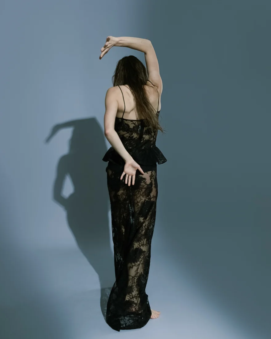 Back view of a black lace gown with the dancer's arm curved overhead, SHOT Magazine editorial photographed by Ina Cenusa