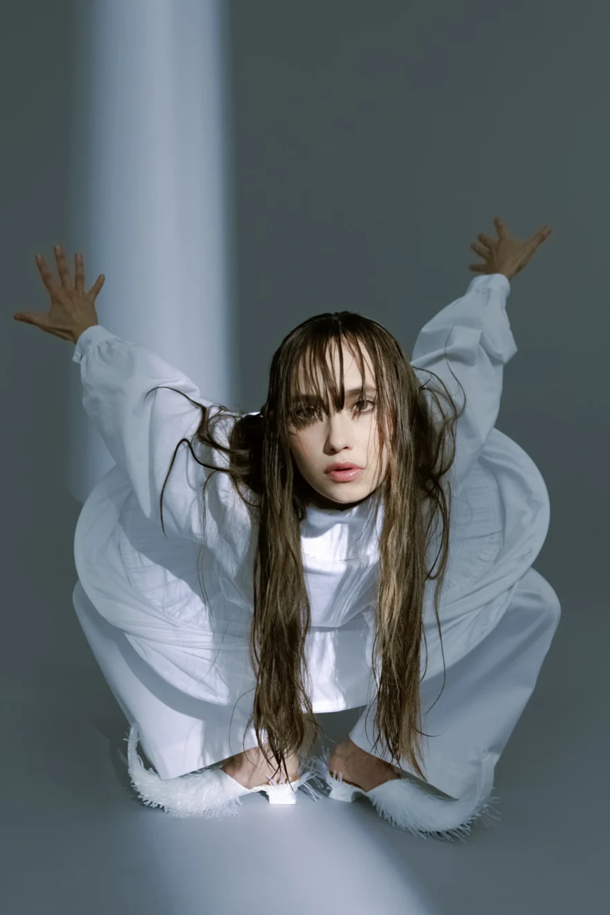 Dancer crouching in a white look with hands raised, SHOT Magazine editorial photographed by Ina Cenusa