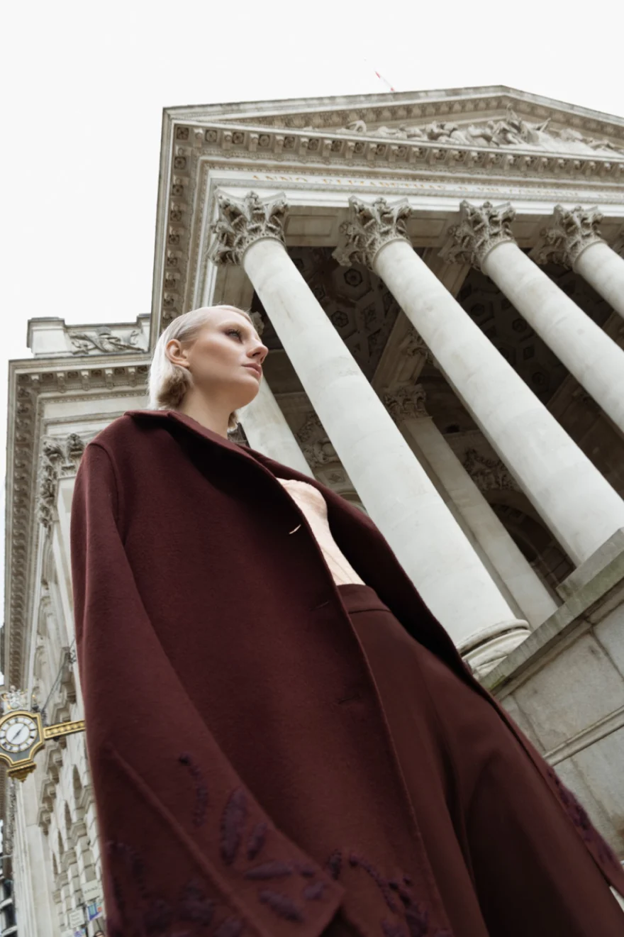 Model in a burgundy cape looking up beneath classical columns, Ermanno Scervino campaign photographed by Ina Cenusa