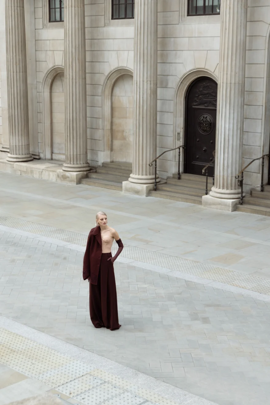 Model in a long burgundy coat on the steps of a classical building, Ermanno Scervino campaign photographed by Ina Cenusa