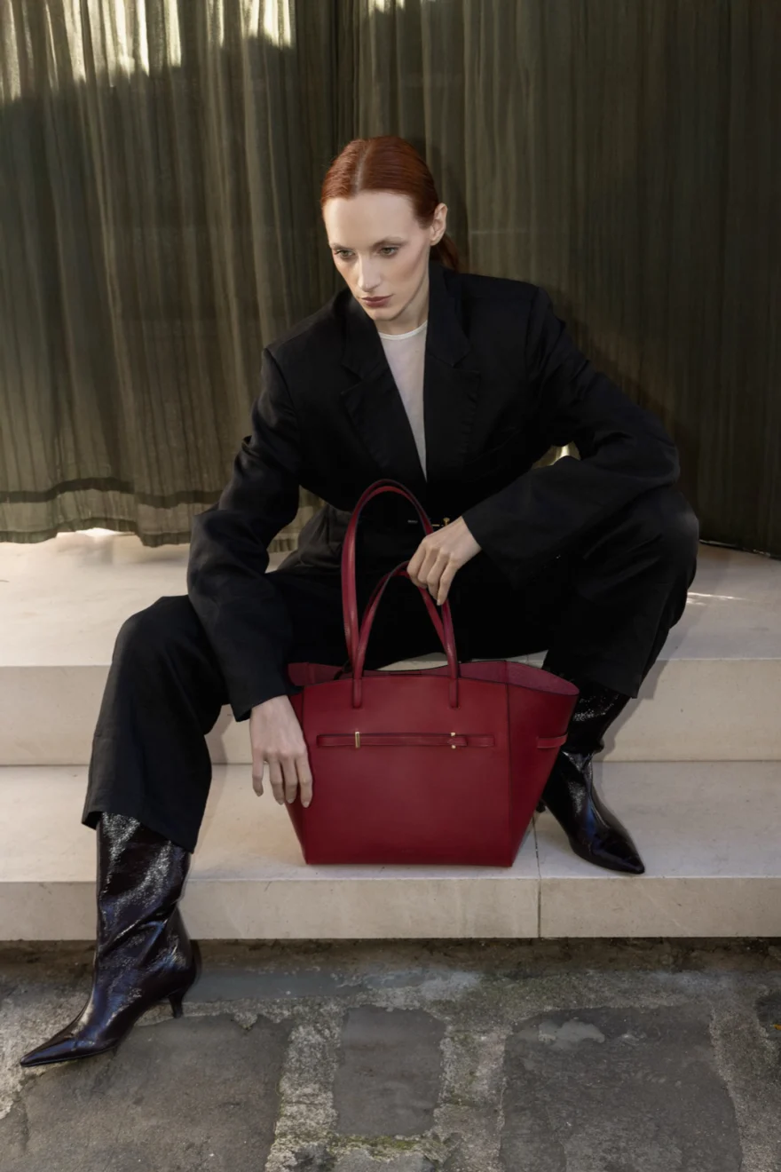 Model seated with a red leather bag against a green curtain, Biebi campaign photographed by Ina Cenusa