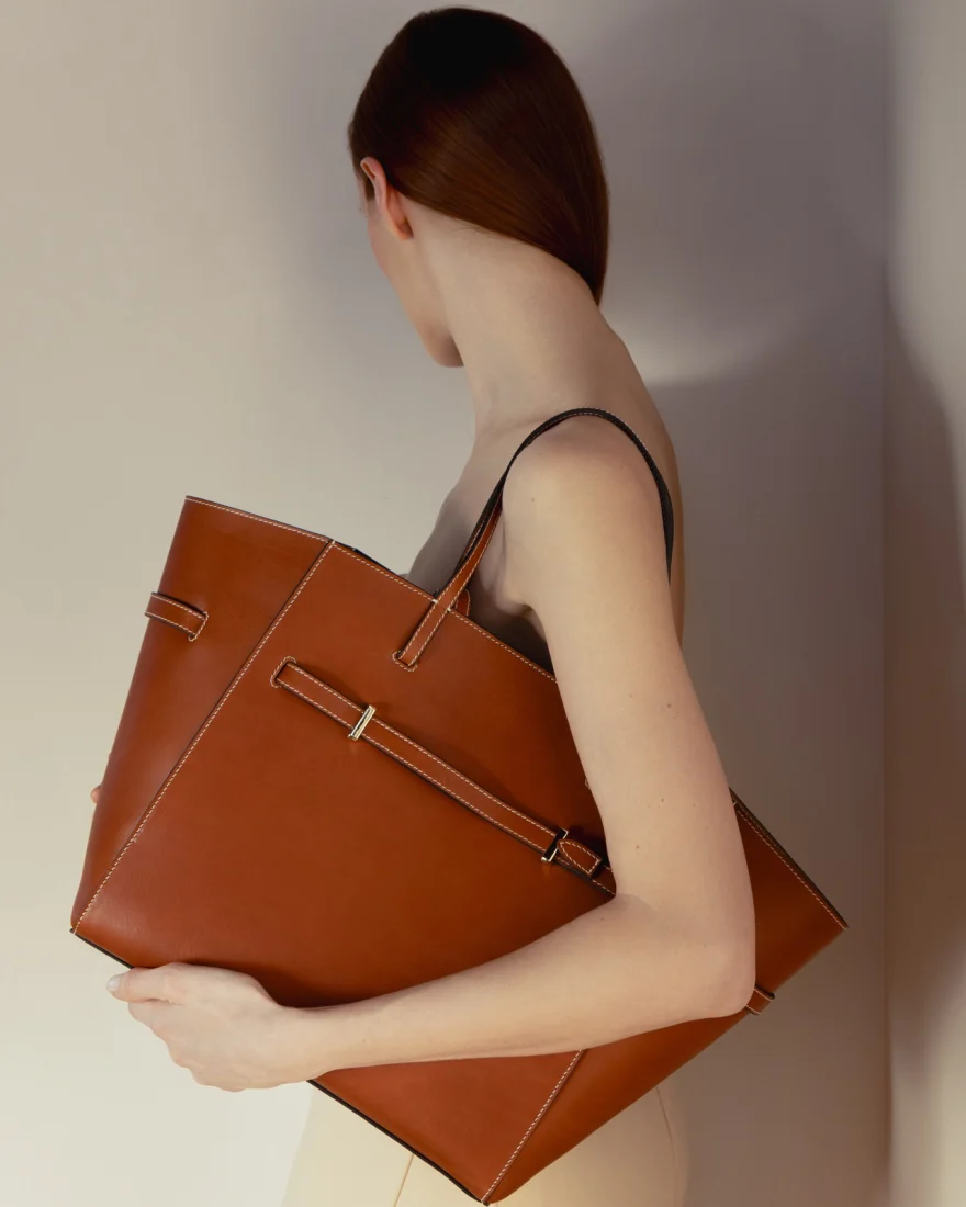 Model with a bare shoulder carrying a tan leather tote, Biebi campaign photographed by Ina Cenusa