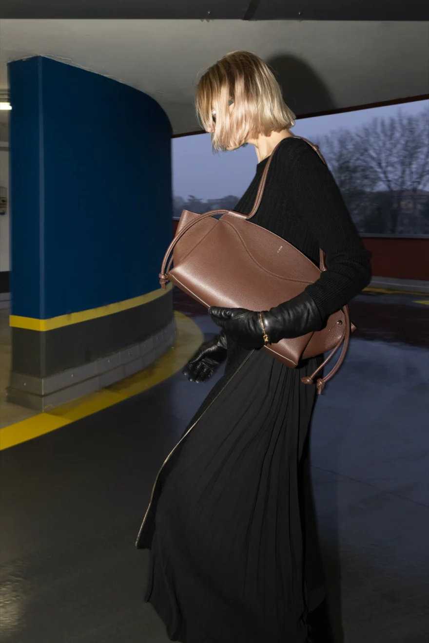 Model with a brown leather shoulder bag in a car park, Noesi campaign photographed by Ina Cenusa