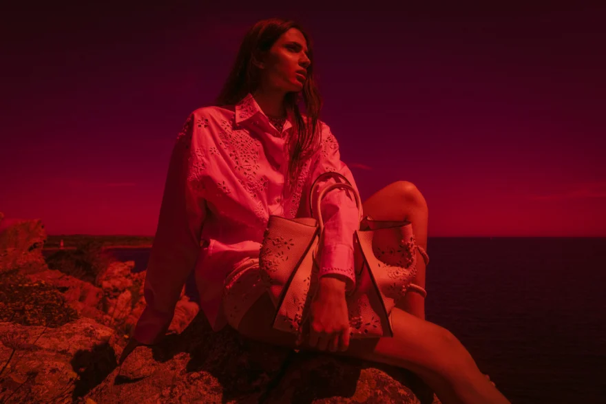 Model standing on a boulder above the water, Ermanno Scervino campaign photographed by Ina Cenusa