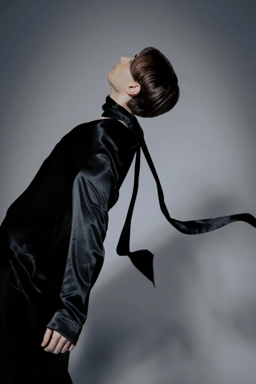 Model arching back in a black satin shirt with a sleek updo, Philip Martin's campaign photographed by Ina Cenusa