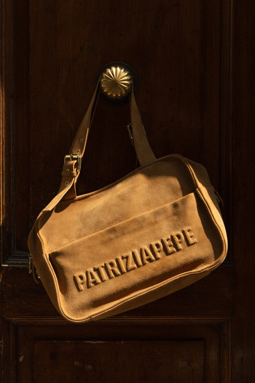 Still life of a gold Patrizia Pepe bag on a dark door, campaign photographed by Ina Cenusa