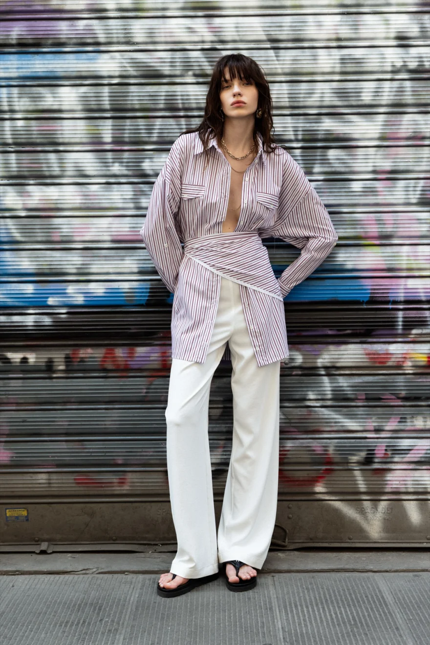 Model in a striped shirt and white trousers against a graffitied shutter, Patrizia Pepe campaign photographed by Ina Cenusa