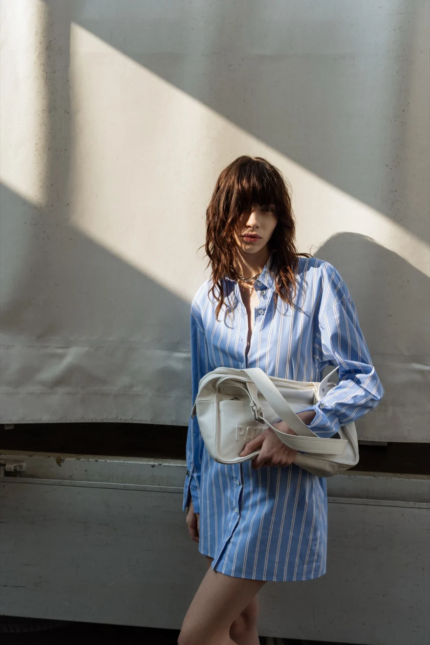 Model in a blue shirt dress carrying a white bag in the sunlight, Patrizia Pepe campaign photographed by Ina Cenusa
