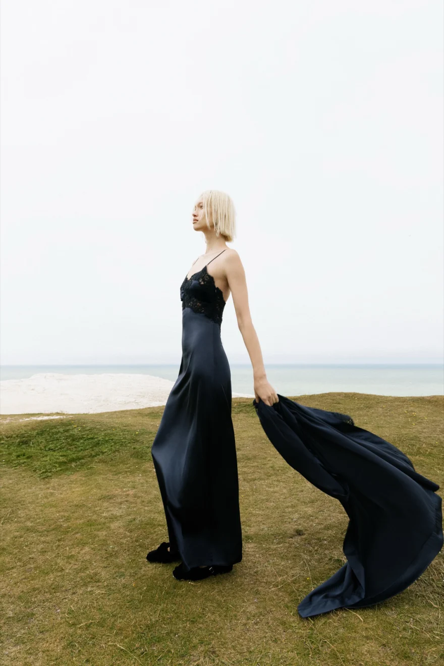 Model in a black bodysuit seated on the grass, Ermanno Scervino campaign photographed by Ina Cenusa