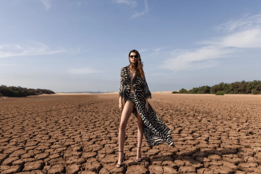 Wide landscape of cracked earth with the model in a dark look, Essaouira, Ermanno Scervino campaign photographed by Ina Cenusa
