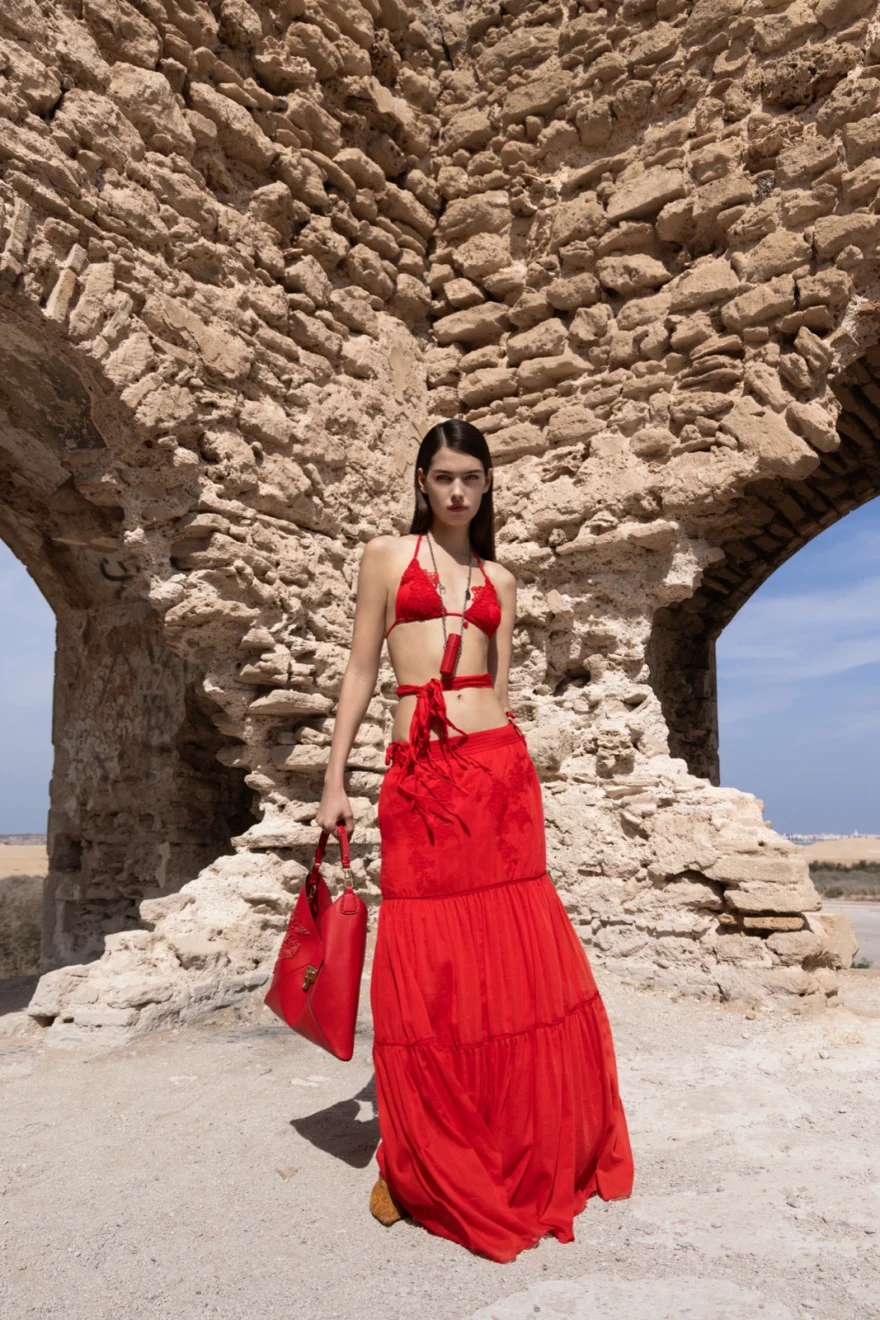 Model in a long red dress framed by a stone arch, Ermanno Scervino Linea Life campaign in Essaouira, Morocco, photographed by Ina Cenusa