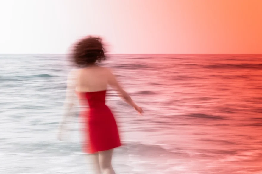 Red dress blurred in movement at the shoreline, Authenticity photographed by Ina Cenusa