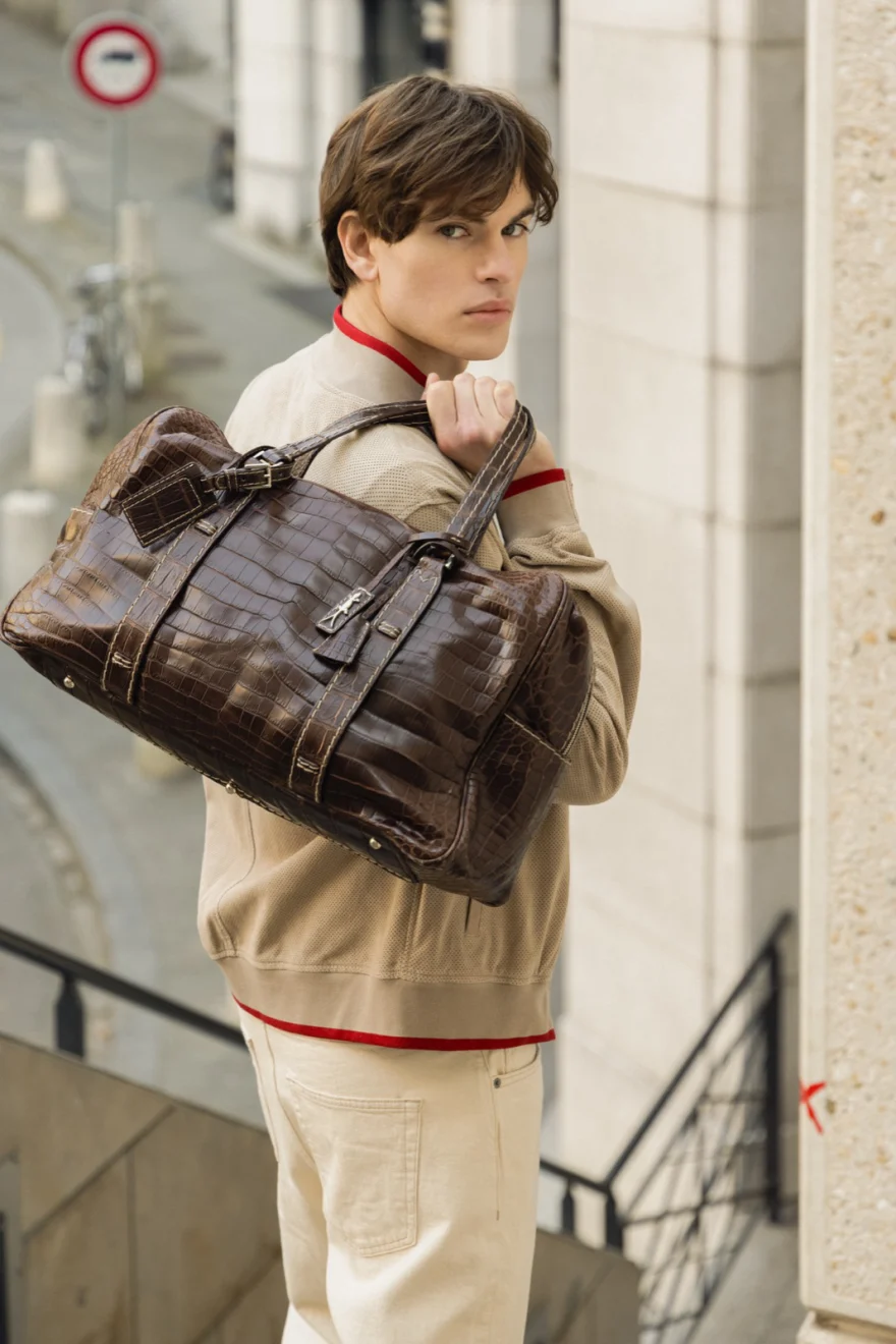 Model carrying a brown leather holdall on a city street, Pagani campaign in Geneva photographed by Ina Cenusa