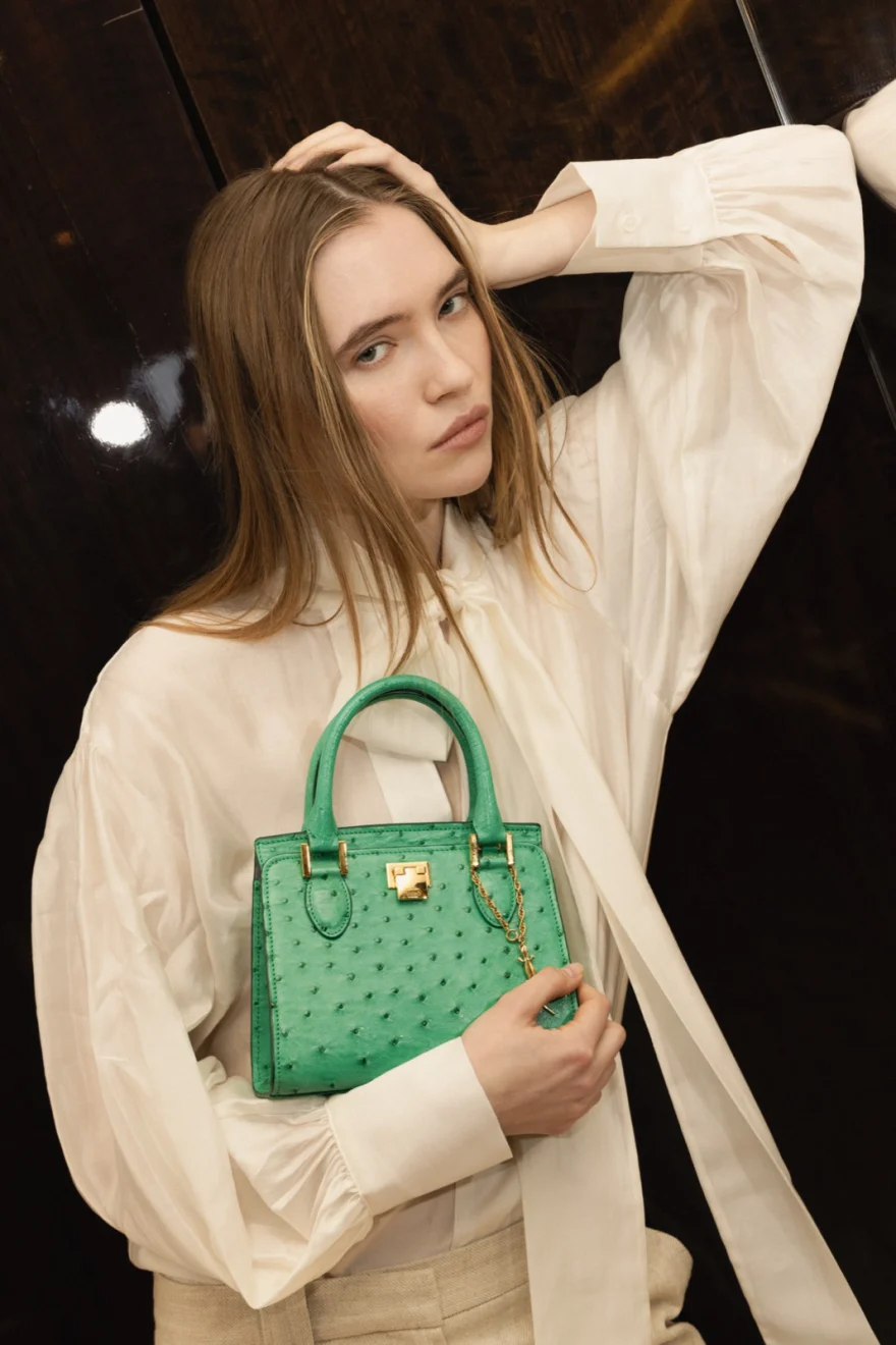 Model holding a green crocodile-effect handbag, Pagani campaign in Geneva photographed by Ina Cenusa