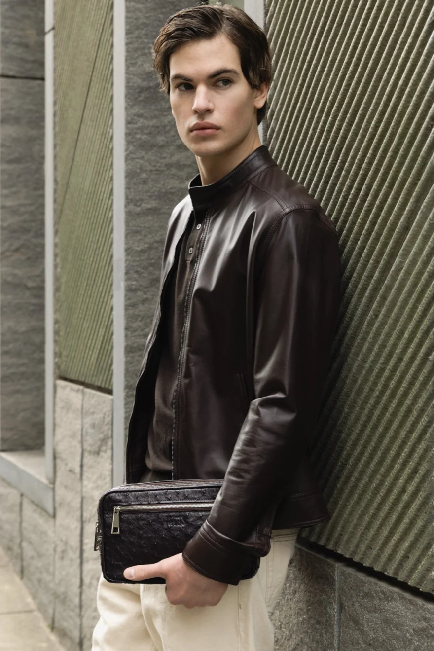 Model in a brown leather jacket holding a matching clutch, Pagani campaign in Geneva photographed by Ina Cenusa
