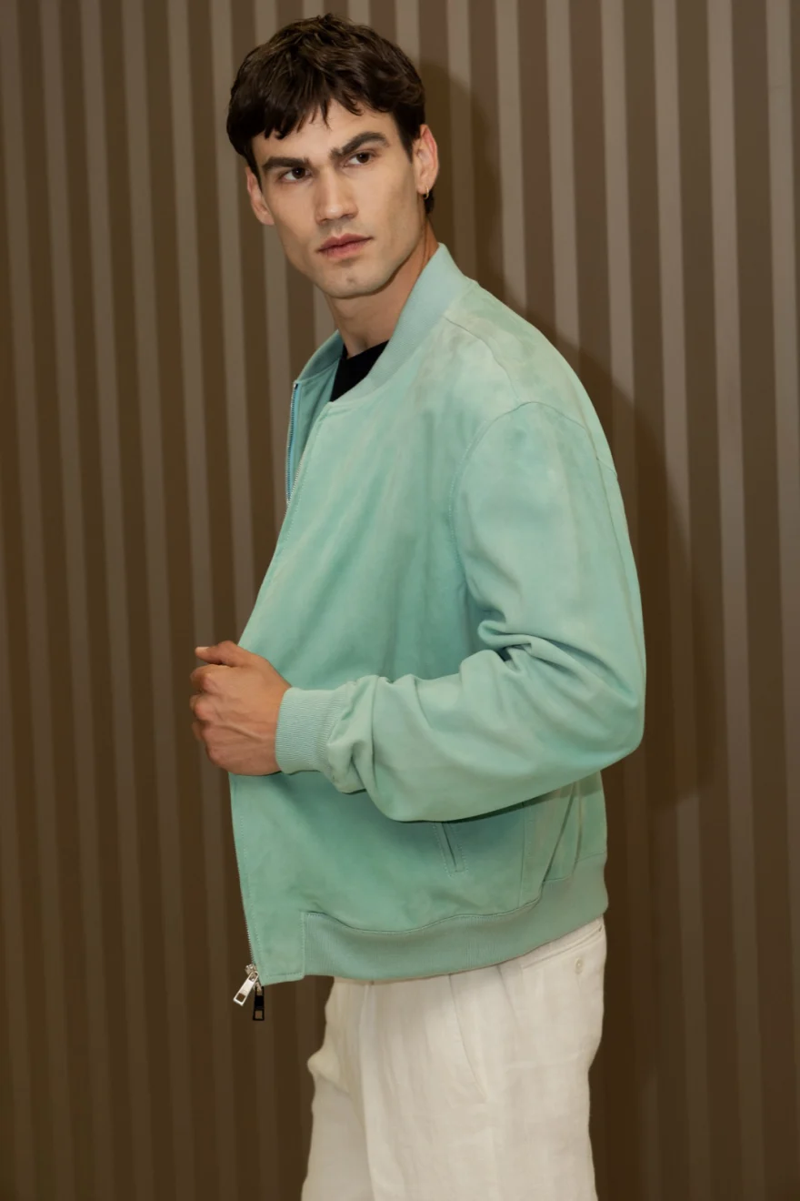 Male model in a mint green bomber and cream trousers against a ribbed brown wall, Pagani campaign in Geneva photographed by Ina Cenusa