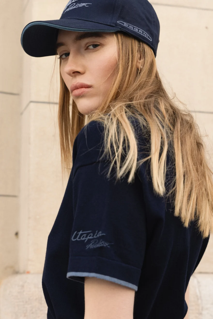 Model in a navy cap and knitted polo looking over her shoulder, Pagani campaign in Geneva photographed by Ina Cenusa