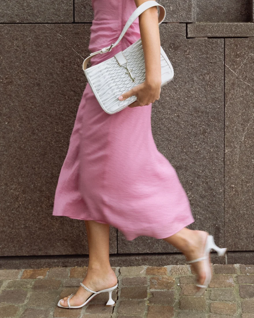 Model in a pink slip dress walking with a white crocodile effect shoulder bag, Pagani campaign in Geneva photographed by Ina Cenusa