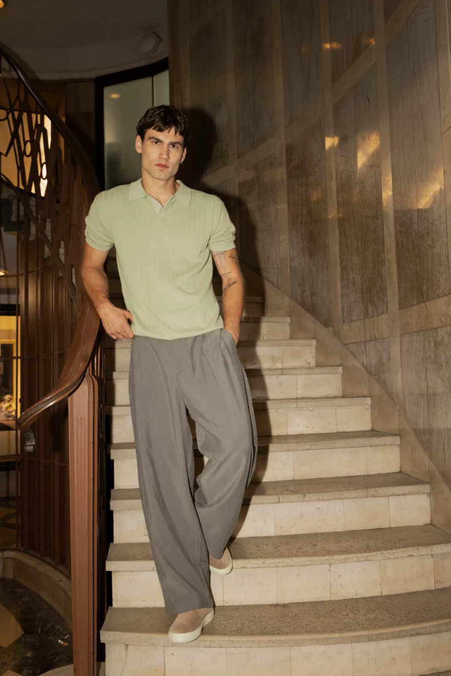 Male model in a sage polo and grey trousers on a marble staircase, Pagani campaign in Geneva photographed by Ina Cenusa