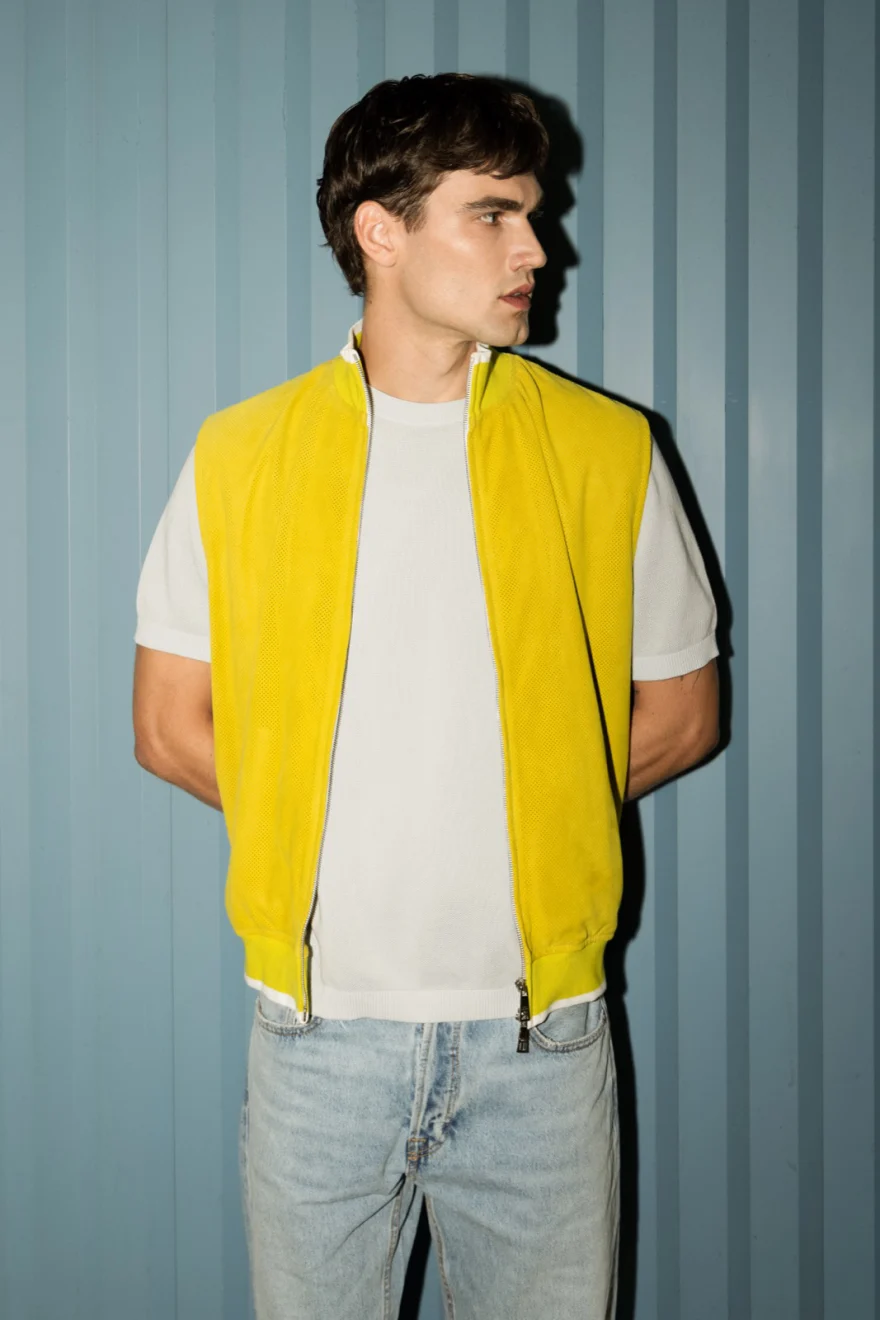 Male model in a yellow gilet over a white tee against a pale blue corrugated wall, Pagani campaign in Geneva photographed by Ina Cenusa