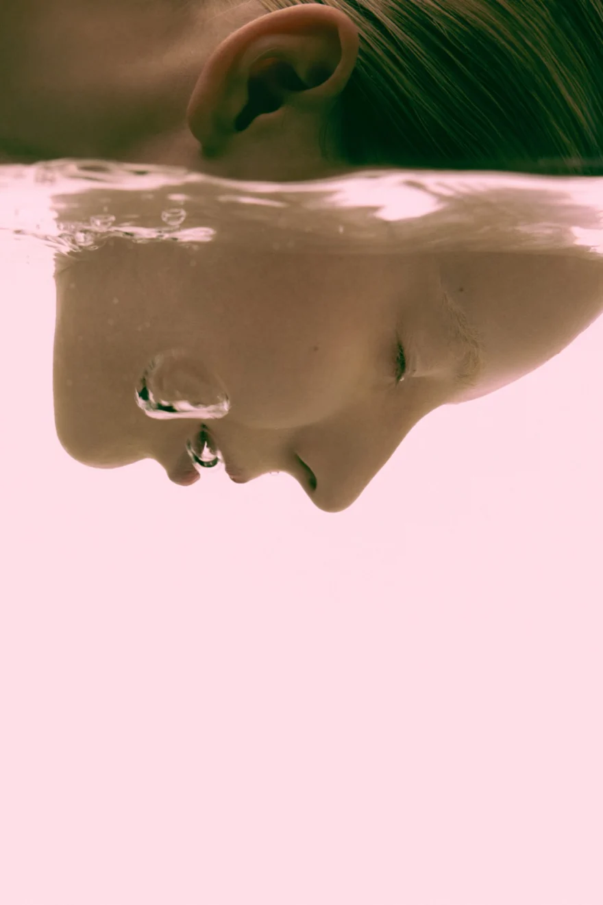 Face half submerged in still water, soft pink light, SHOT Magazine photographed by Ina Cenusa